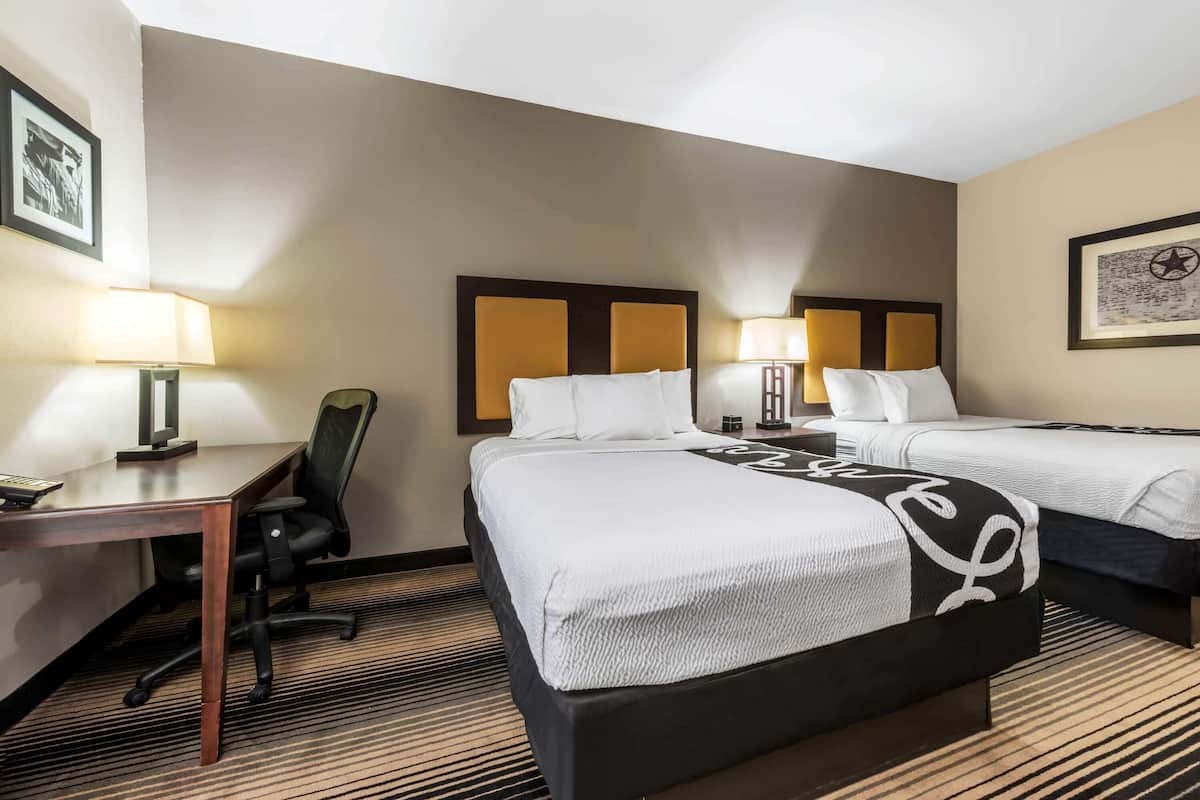 Ett hotellrum med två sängar, ett skrivbord och en stol.