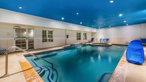 A swimming pool with a blue-tiled edge, a blue cover on one side, and a handrail.