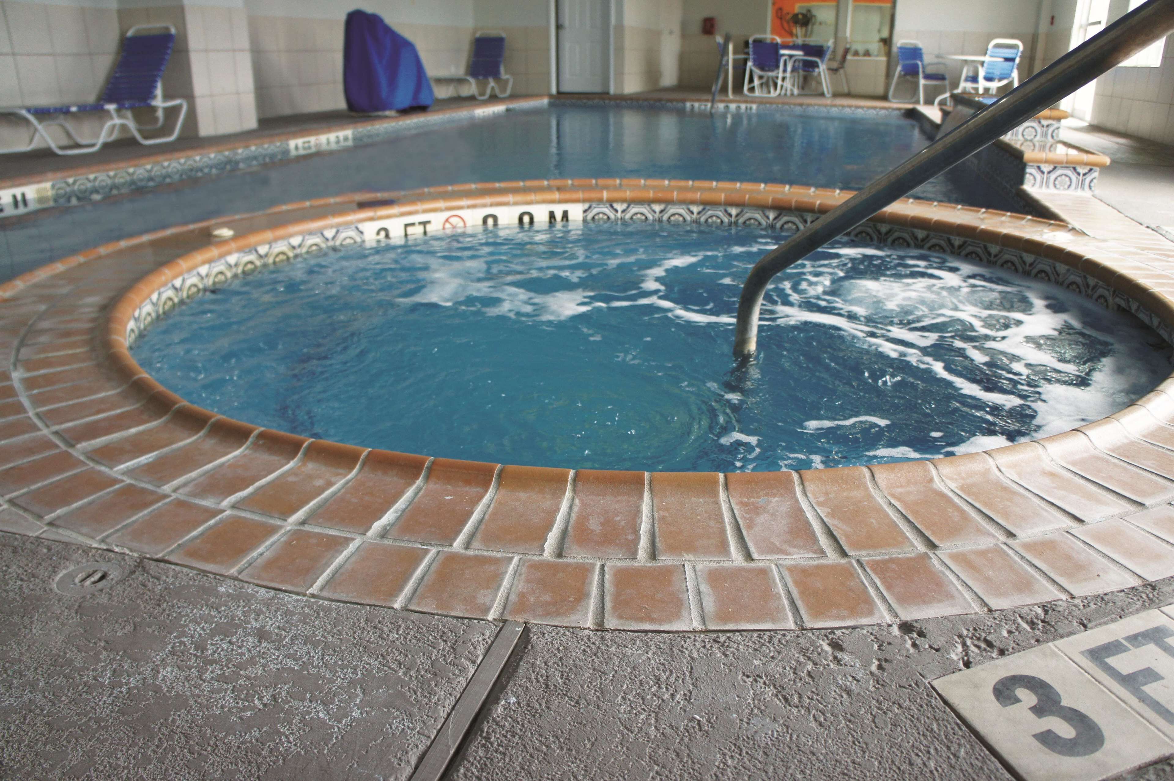 A hot tub with a tiled edge and a metal pole.