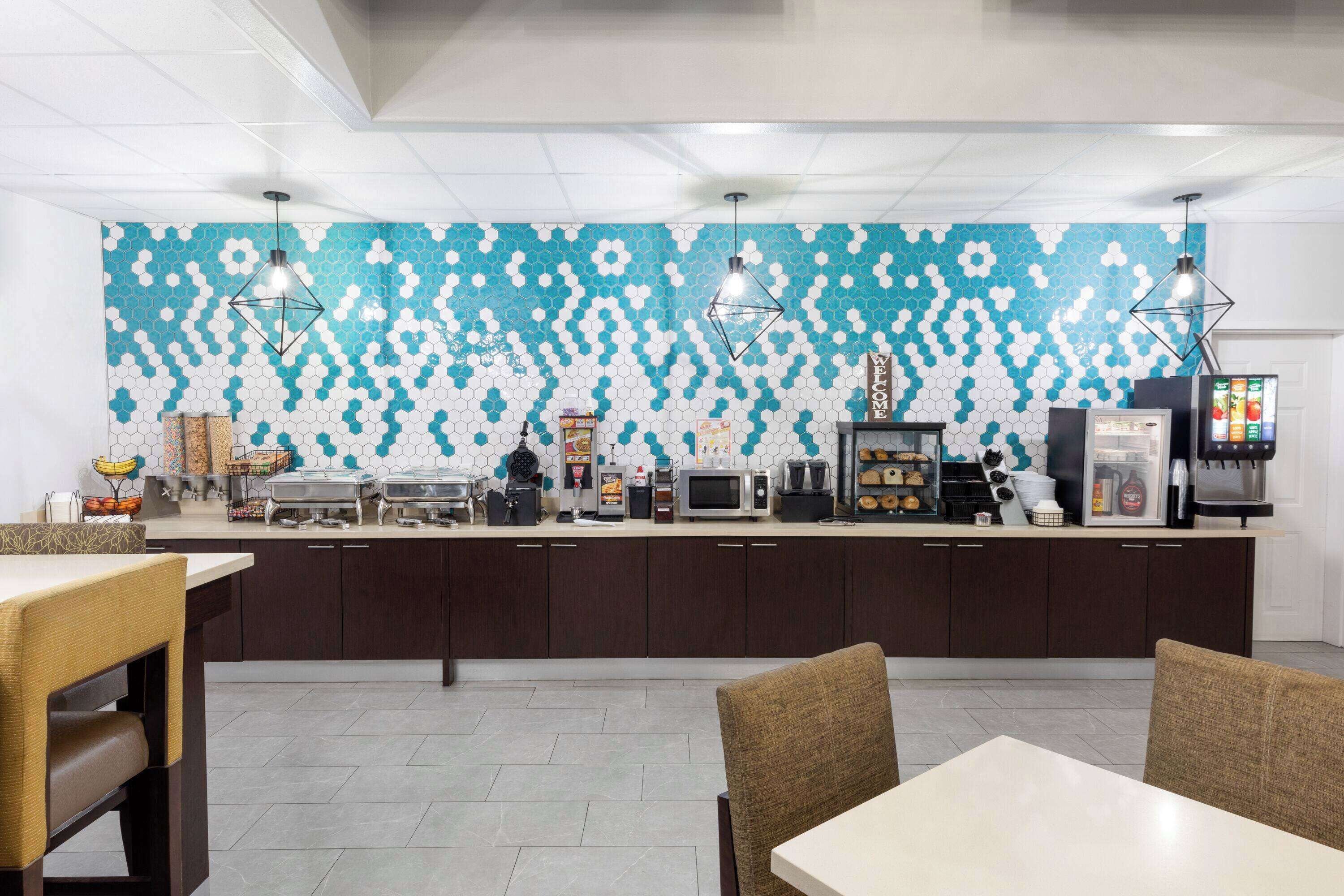 A modern kitchen with a hexagonal tile backsplash, stainless steel appliances, and pendant lighting.