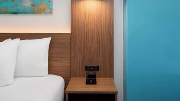 Una cama bien hecha con sábanas blancas, una mesita de noche de madera con una radio negra y una pared color aguamarina.