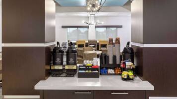 A modern kitchen with a coffee station featuring decaffeinated and regular coffee options, a variety of coffee pods, and a decorative light fixture.