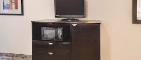 Un mobile in legno scuro con una televisione sopra e un forno a microonde all'interno.
