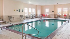 An indoor swimming pool with tiled flooring, metal pool ladders, and several chairs and benches around the pool area. - La Quinta Inn & Suites by Wyndham Glen Rose (Glen Rose)