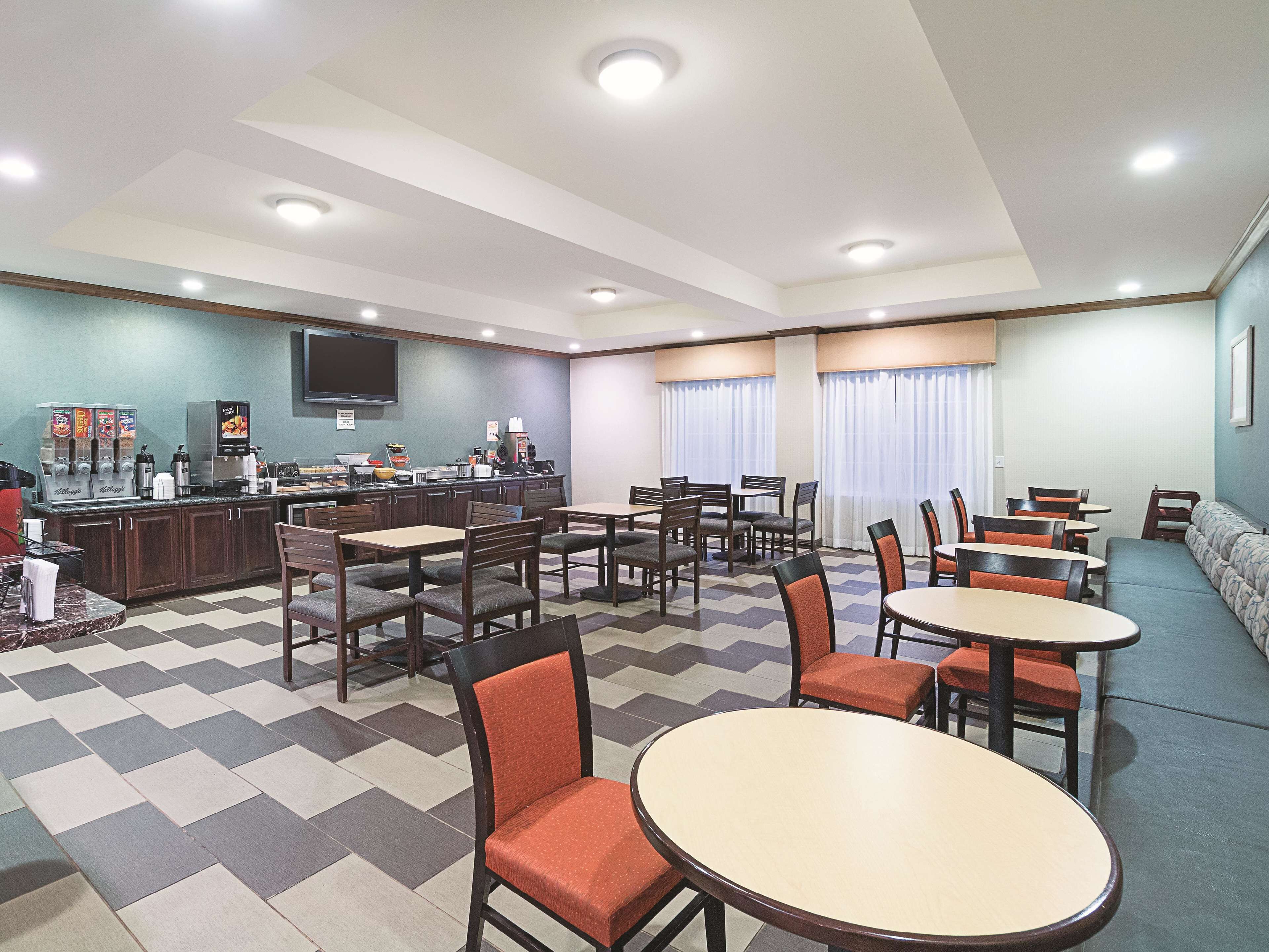 A hotel lobby with a bar area, seating arrangements, and a television mounted on the wall.