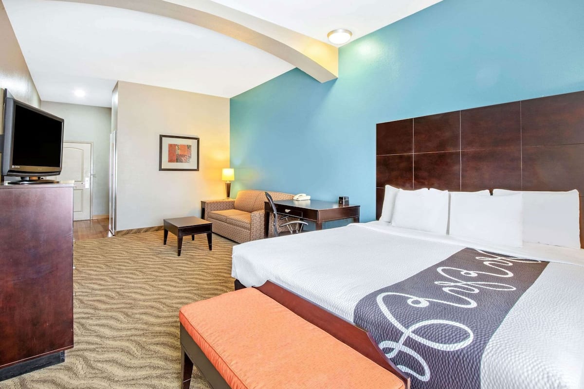 Une chambre d’hôtel équipée d’un lit, d’un bureau, d’une chaise, d’une télévision et d’une œuvre d’art accrochée au mur.