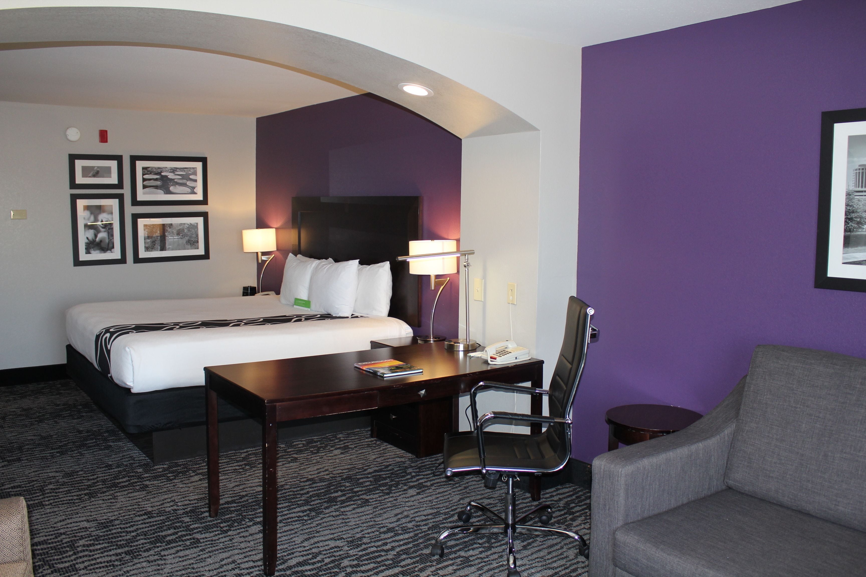 Una habitación de hotel con cama, escritorio, silla y sofá.
