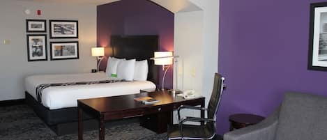 Una habitación de hotel con cama, escritorio, silla y sofá.