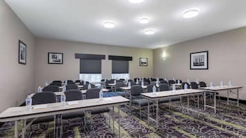 A conference room with multiple tables, chairs, and water bottles.