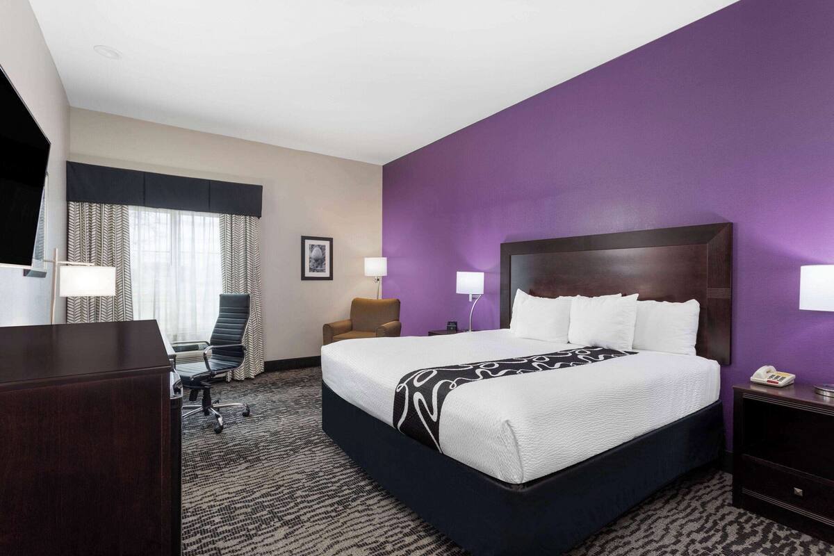 A hotel room with a large bed, a desk, and a chair.