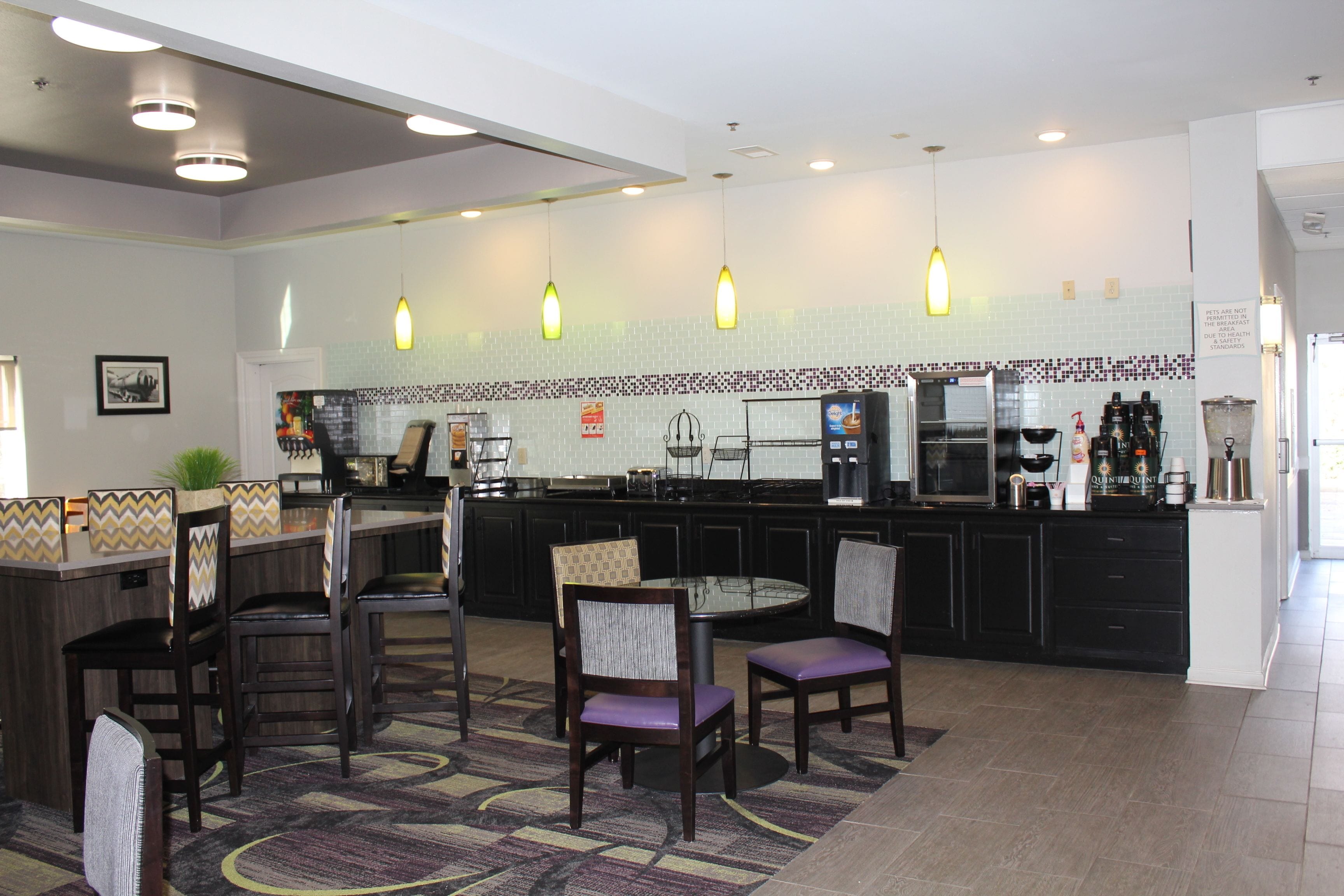 Une cuisine moderne dotée d’un îlot central, de sièges de bar et de luminaires suspendus.