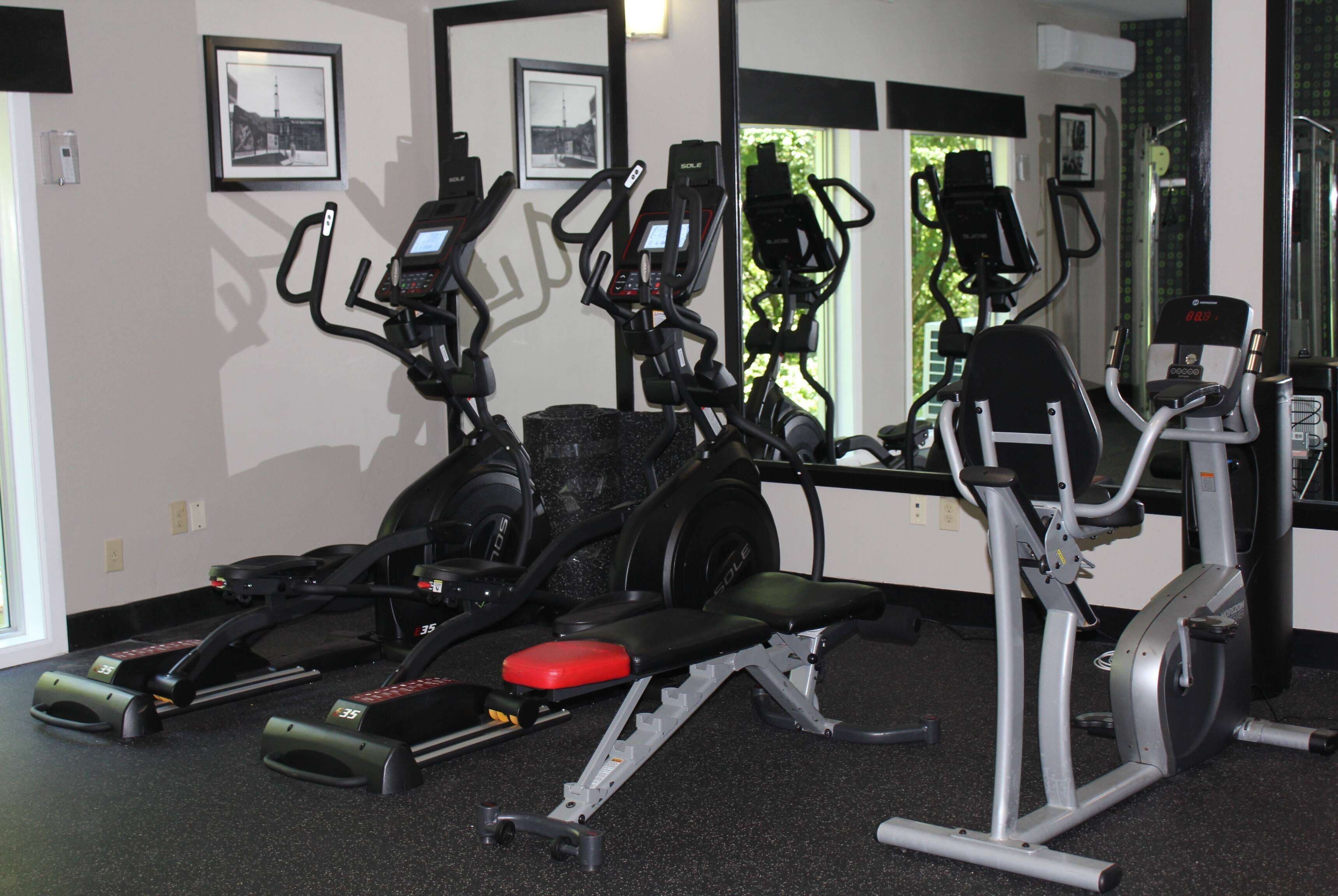 A gym with stationary bikes, a treadmill, and a bench press.