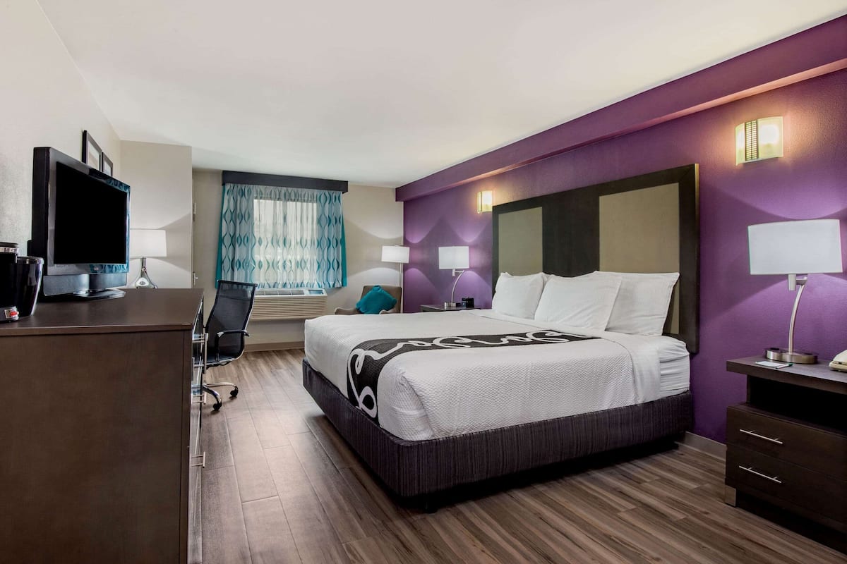 Une chambre d’hôtel avec un lit, un bureau et une télévision.
