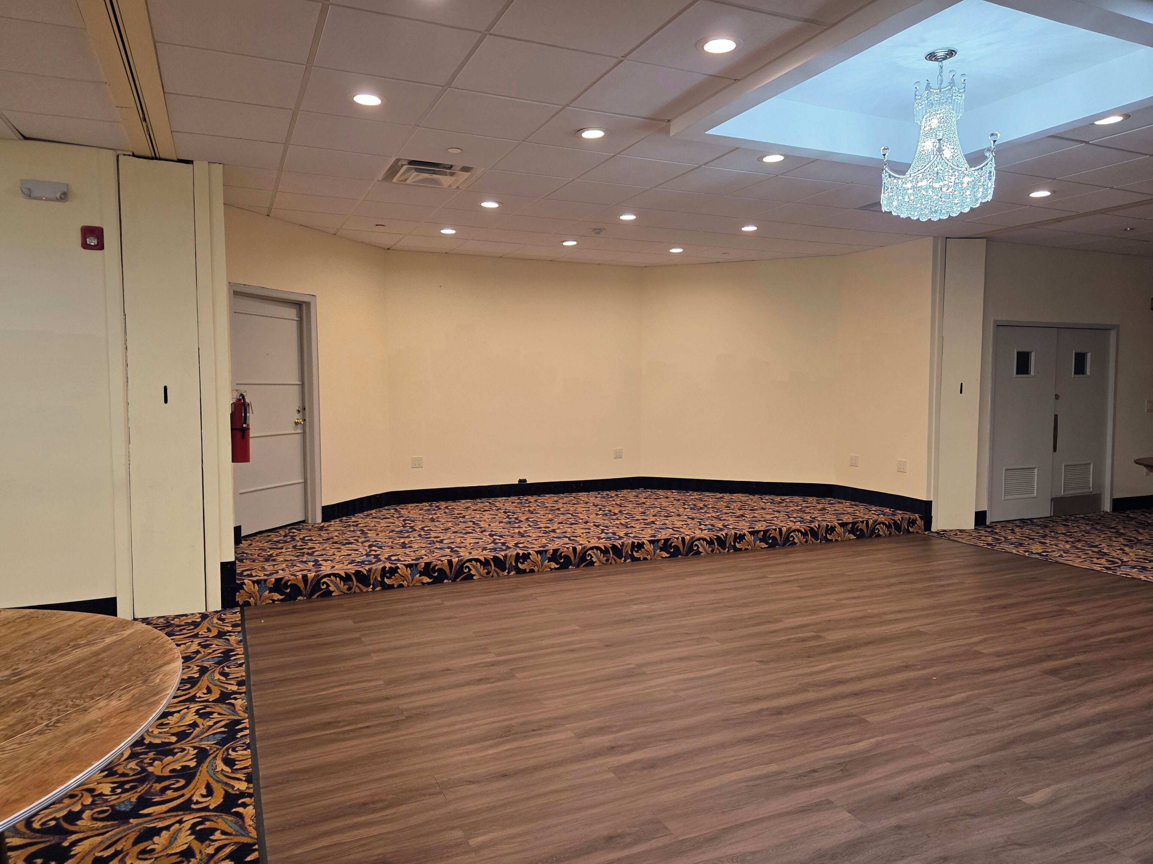Una sala de conferències amb un mosaic a la llosa, una làmpada de cristall i un extintor.