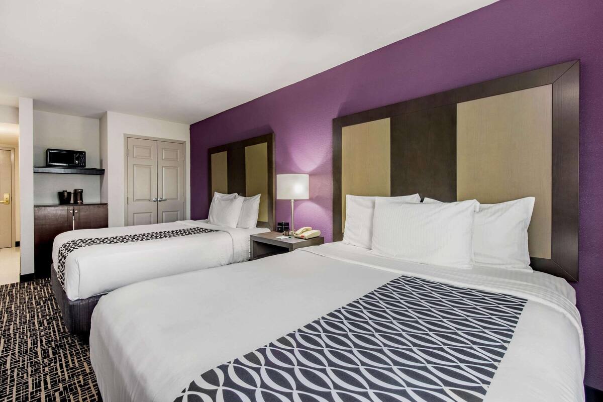 Une chambre d’hôtel avec deux lits, un bureau, un four à micro-ondes et une armoire.