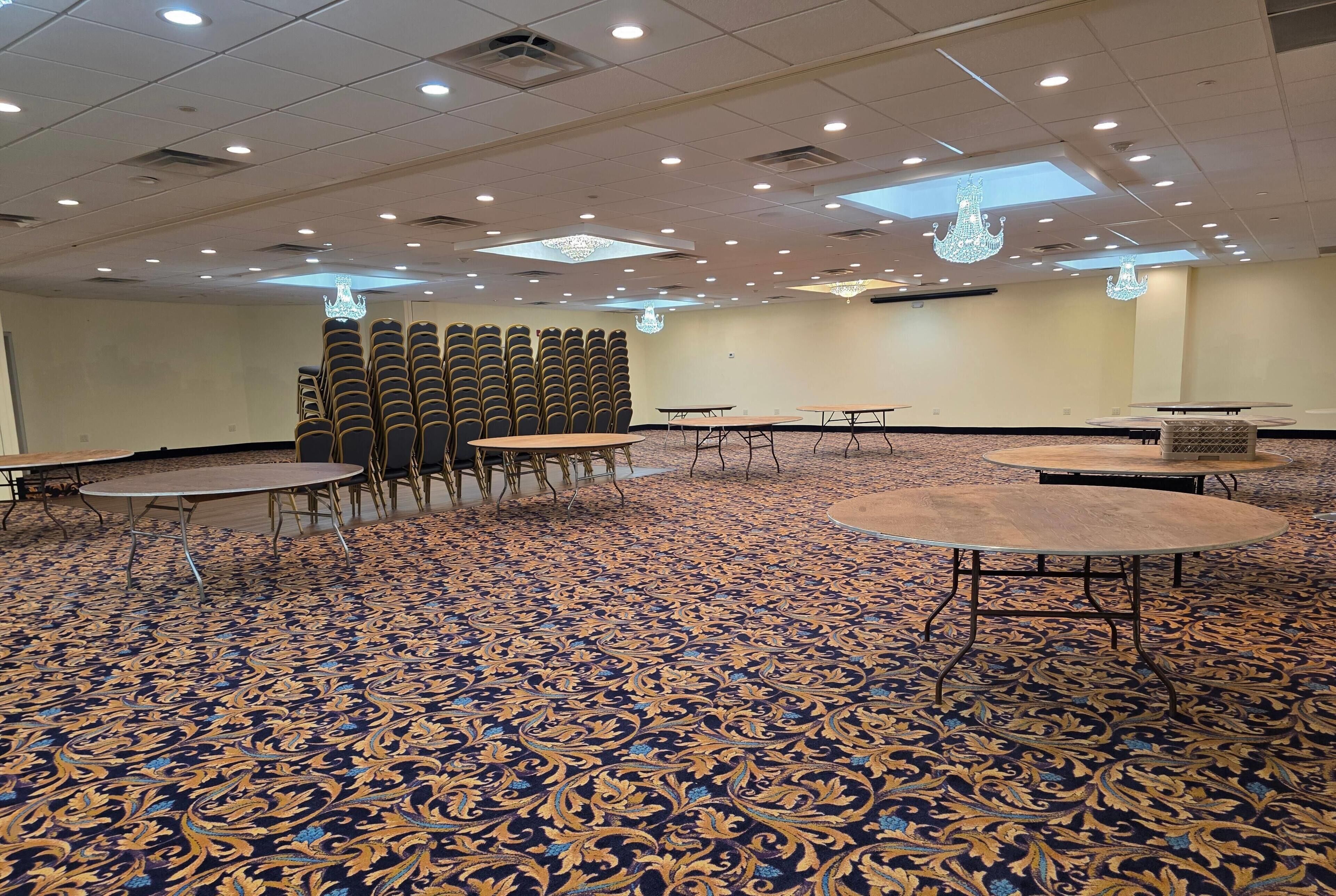 A conference room with a patterned carpet, round tables, and chairs arranged for meetings.