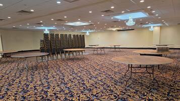 A conference room with a patterned carpet, round tables, and chairs arranged for meetings.