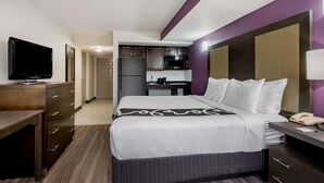 Une chambre d’hôtel équipée d’un lit, d’un bureau, d’une télévision, d’une kitchenette et d’une salle de bain.