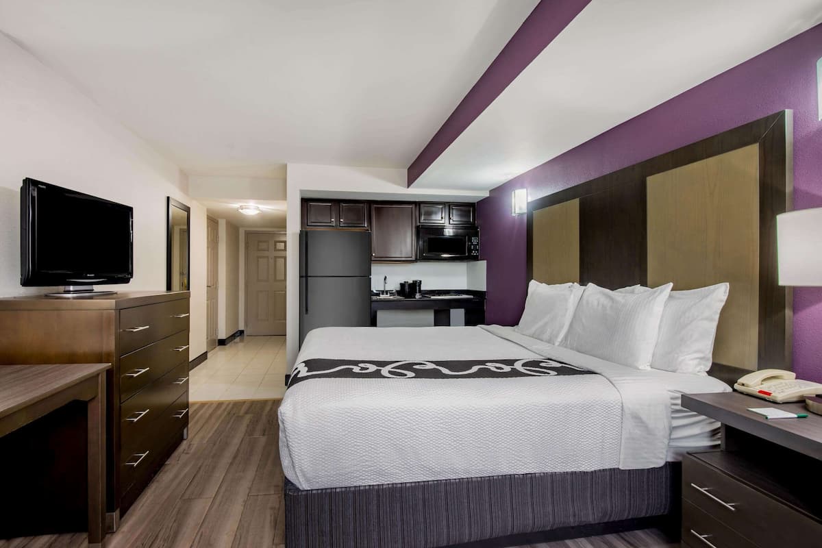 Une chambre d’hôtel équipée d’un lit, d’un bureau, d’une télévision, d’une kitchenette et d’une salle de bain.