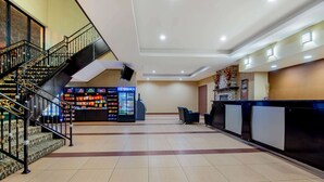 Un hall d’hôtel avec un distributeur automatique de Pepsi, un comptoir d’accueil et un escalier.