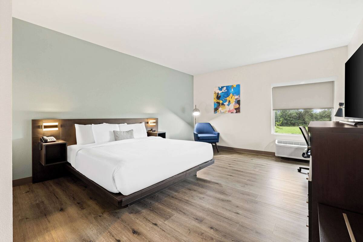 A modern hotel room with a large bed, bedside tables, a desk, and a chair.