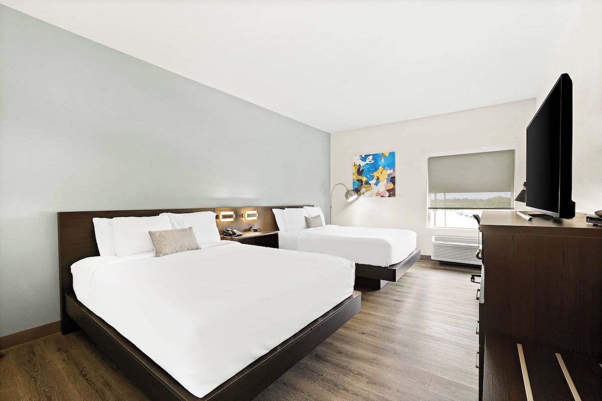A hotel room with a large bed, a smaller bed, a desk, a television, and a window with a view.