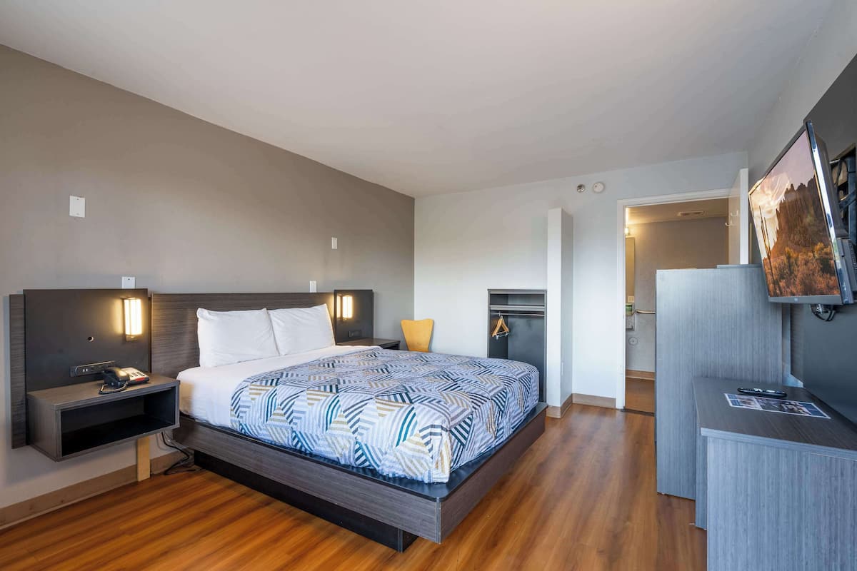Una habitación de hotel moderna con una cama grande, mesitas de noche, un escritorio y un televisor de pantalla plana.