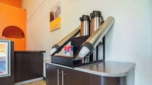 Een kitchenette met roestvrijstalen apparatuur, een koffieapparaat en een suikerpot.