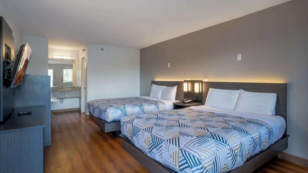Een hotelkamer met twee bedden, een bureau en een badkamer op de achtergrond.