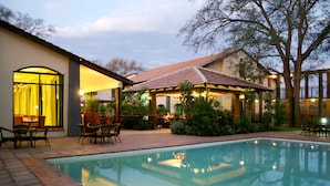 A swimming pool with a patio area, outdoor seating, and a covered section with string lights. - Protea Hotel by Marriott Livingstone (Livingstone)