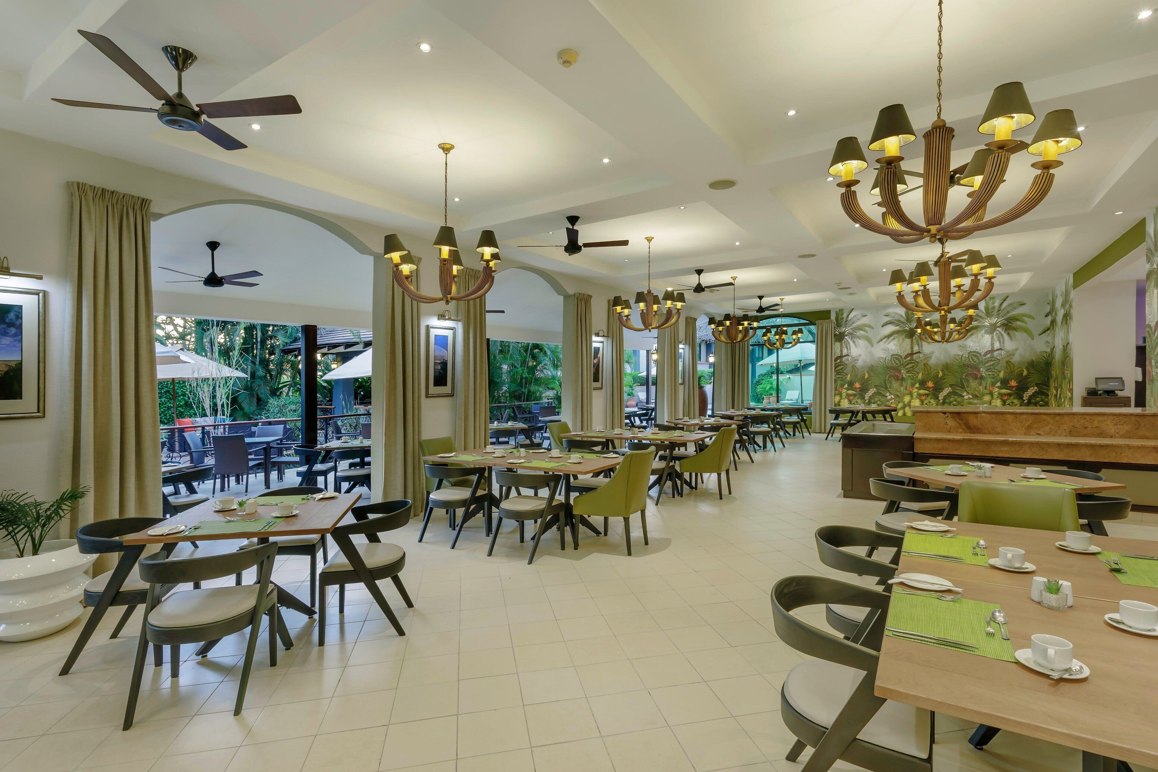 A spacious dining area with multiple tables and chairs, ceiling fans, and a large chandelier.