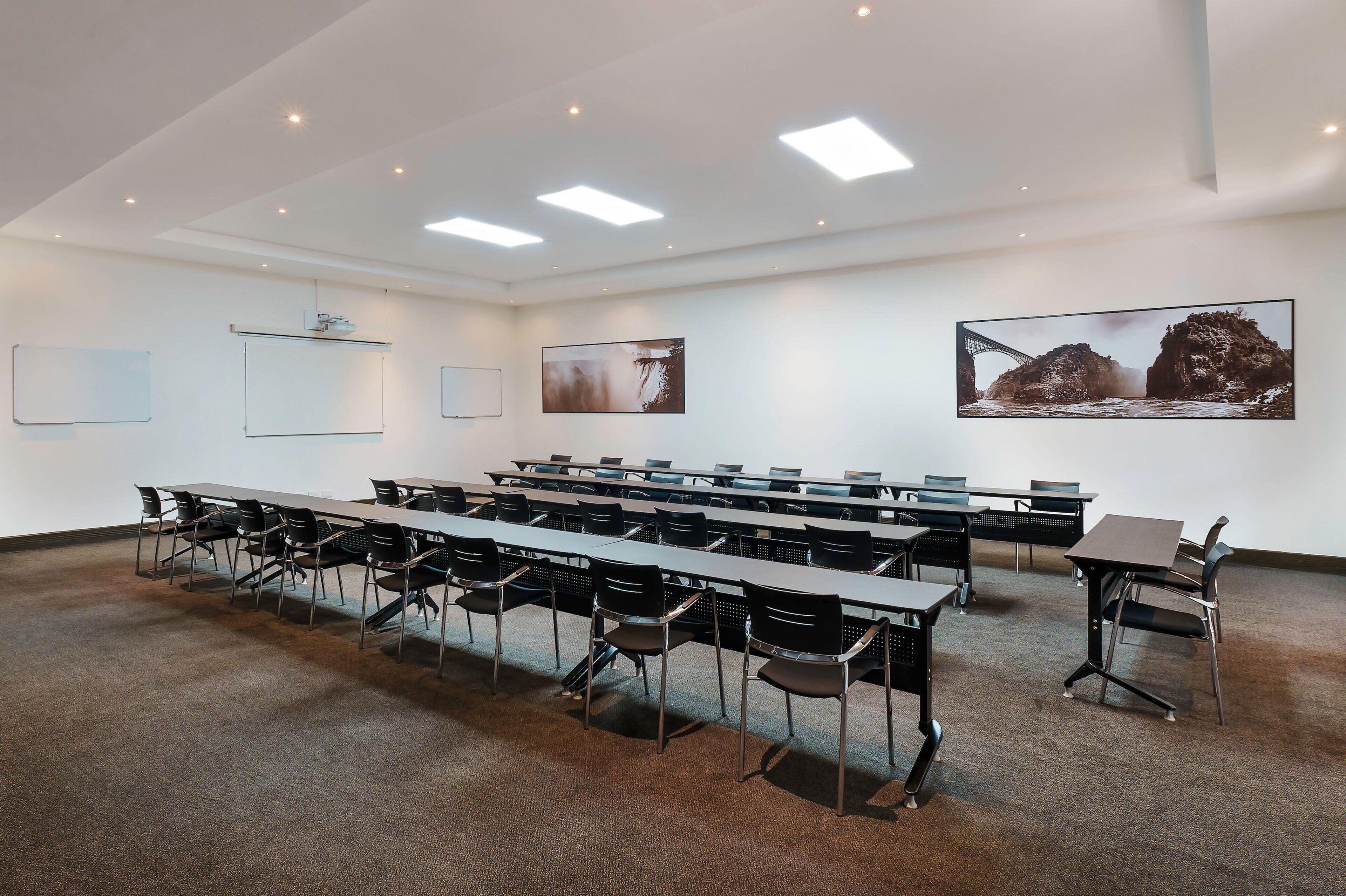 A conference room with long tables and chairs, white walls, and ceiling lights.
