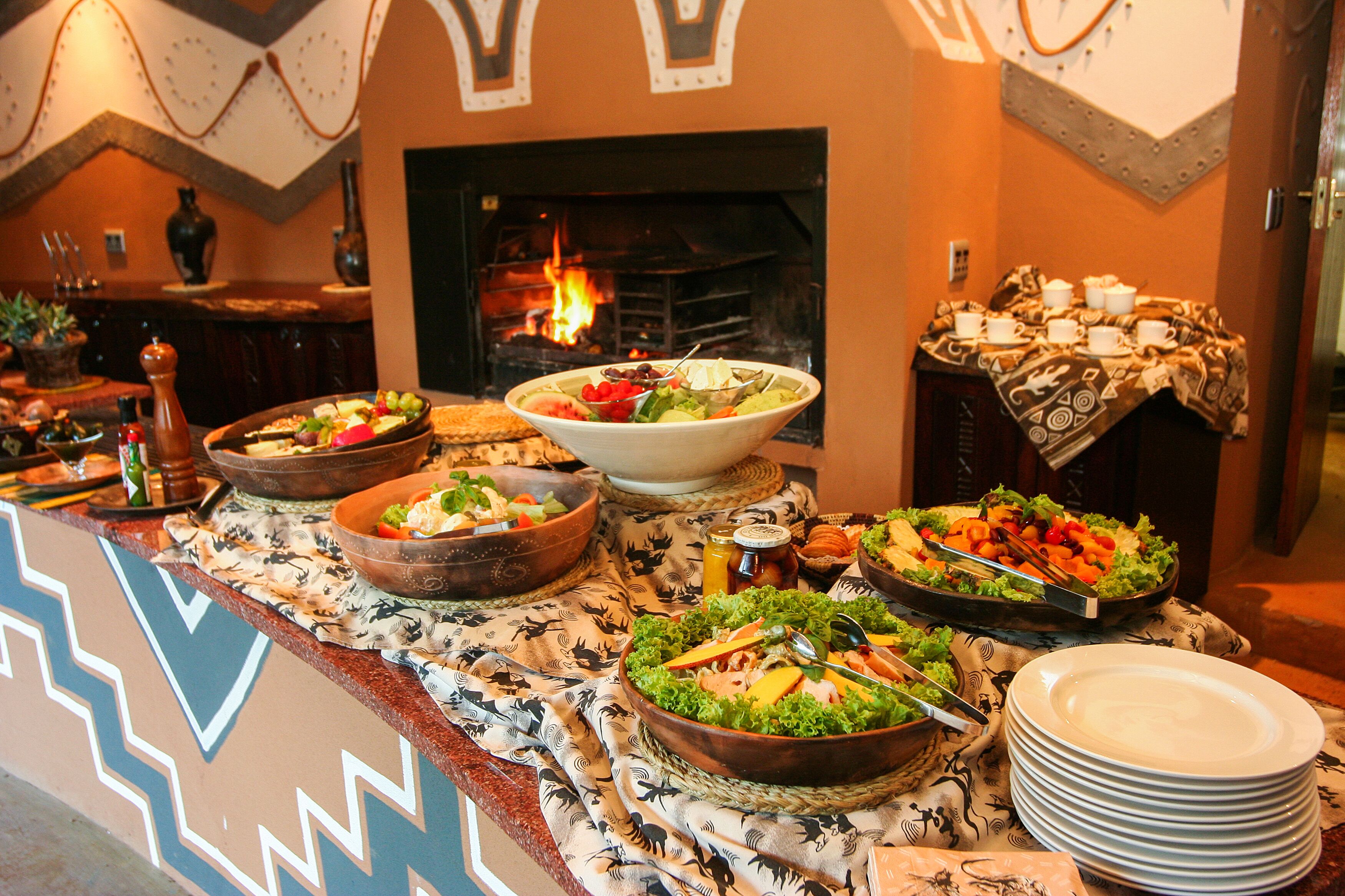 A buffet setup with various dishes and a fireplace in the background.