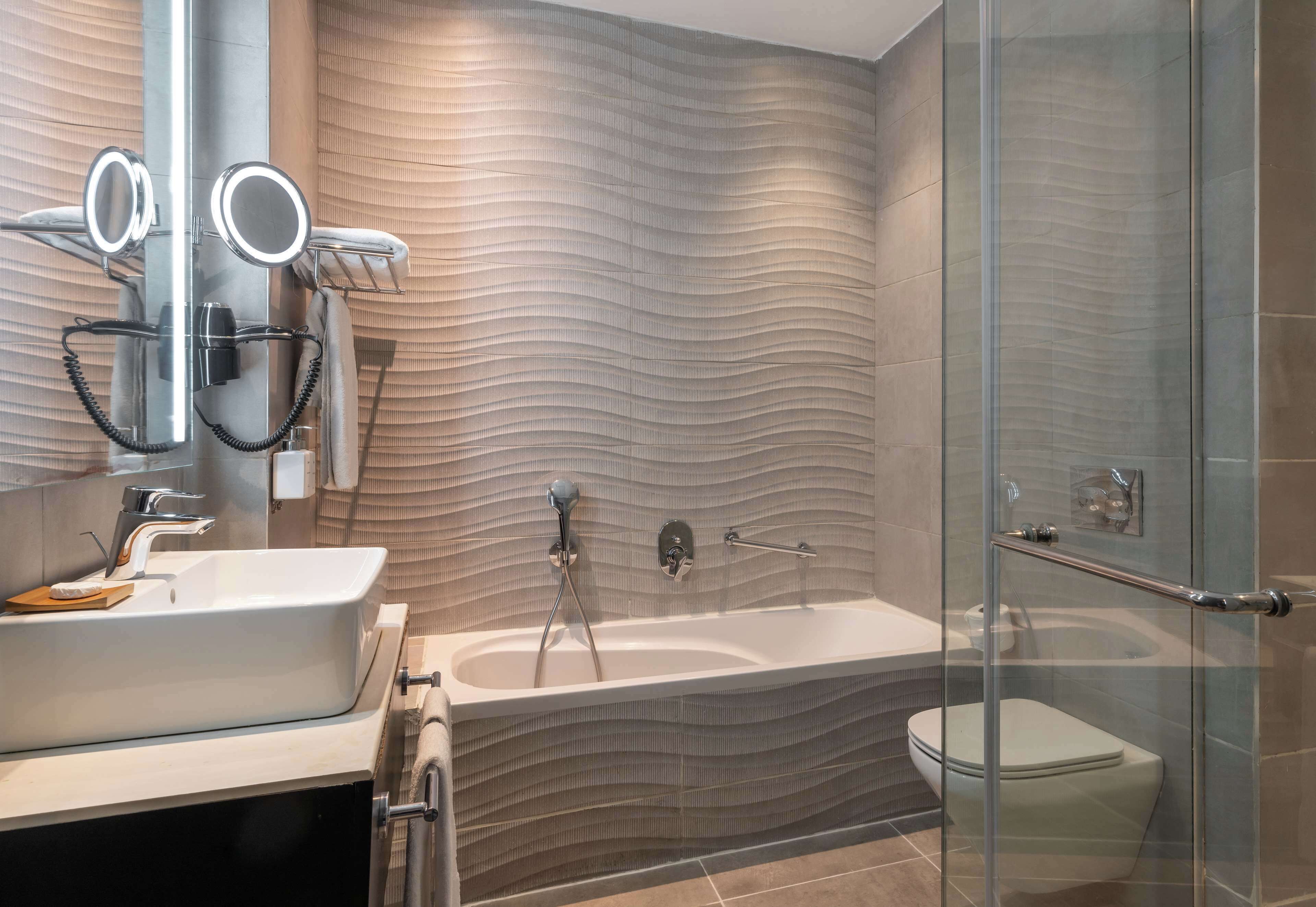 Ein modernes Badezimmer mit einer großzügigen Badewanne, einer Duschkabine und einem Waschtisch mit Spiegel.