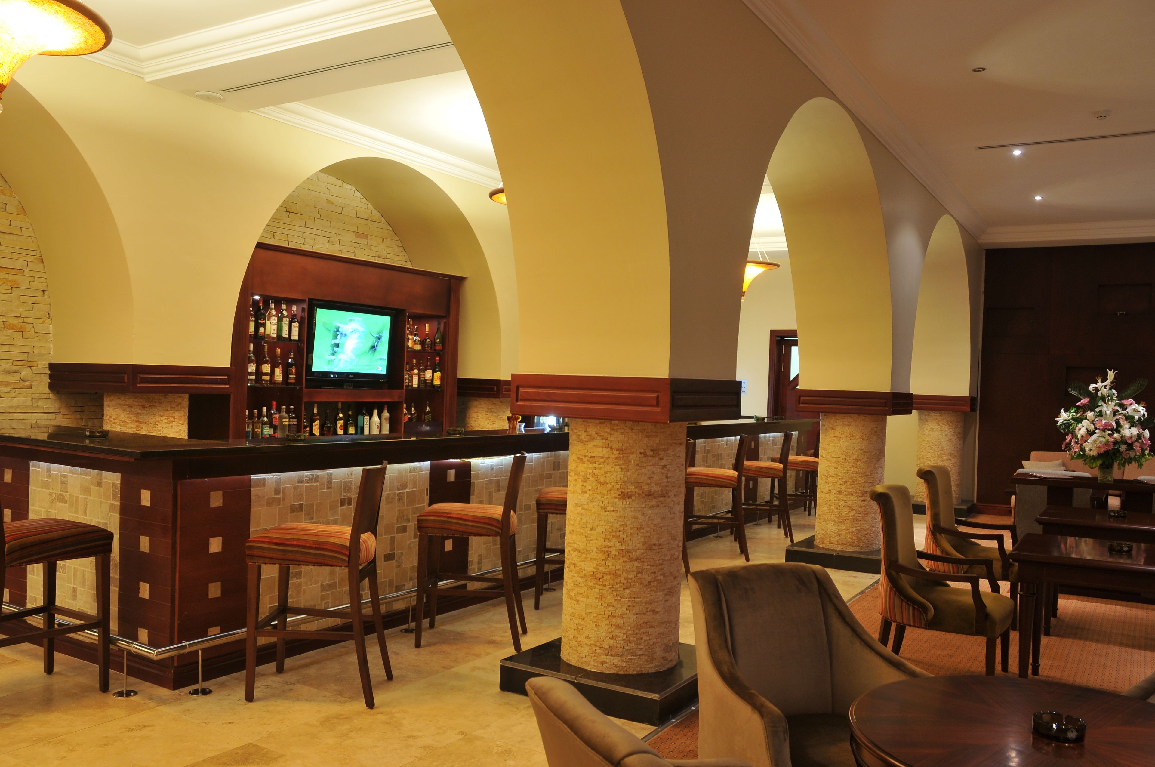A bar area with a television, bar stools, and a seating area with chairs and tables.
