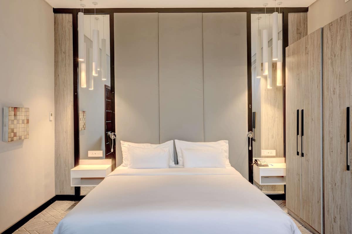 A modern bedroom with a large bed, a wardrobe, and a mirror.