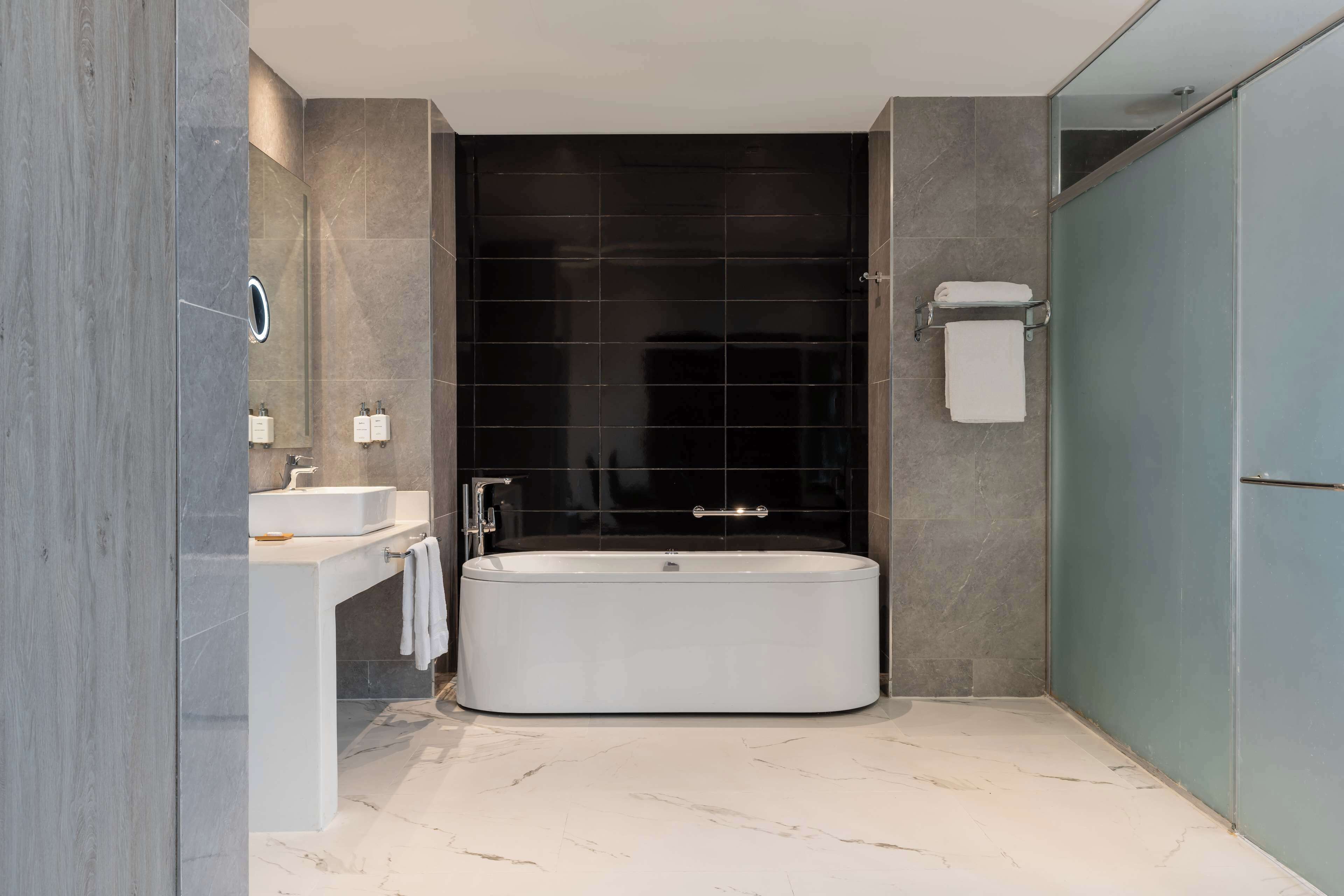 A modern bathroom with a freestanding bathtub, a vanity with a mirror, and a towel rack.