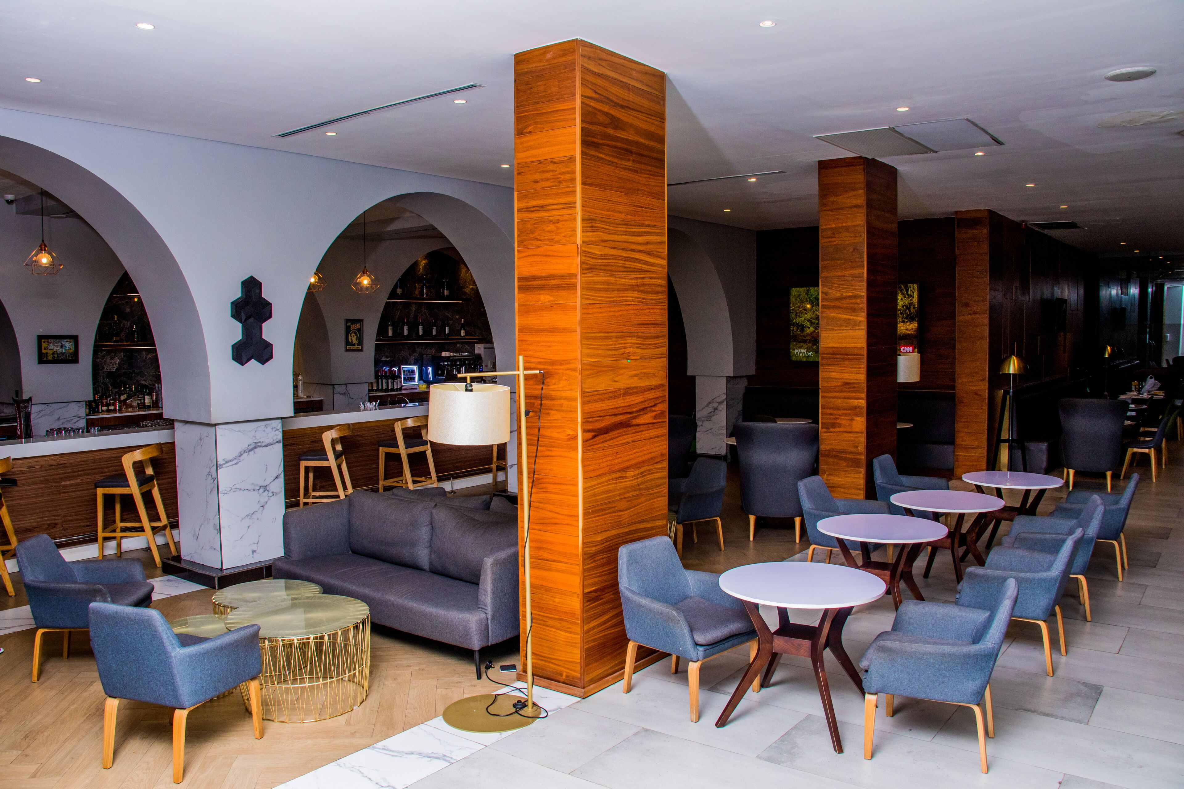 Un espace de détente moderne comprenant un bar, des canapés et des tables rondes.