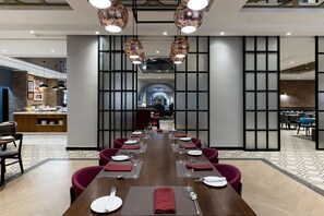 A modern dining area with a long wooden table set for a meal, surrounded by red chairs.