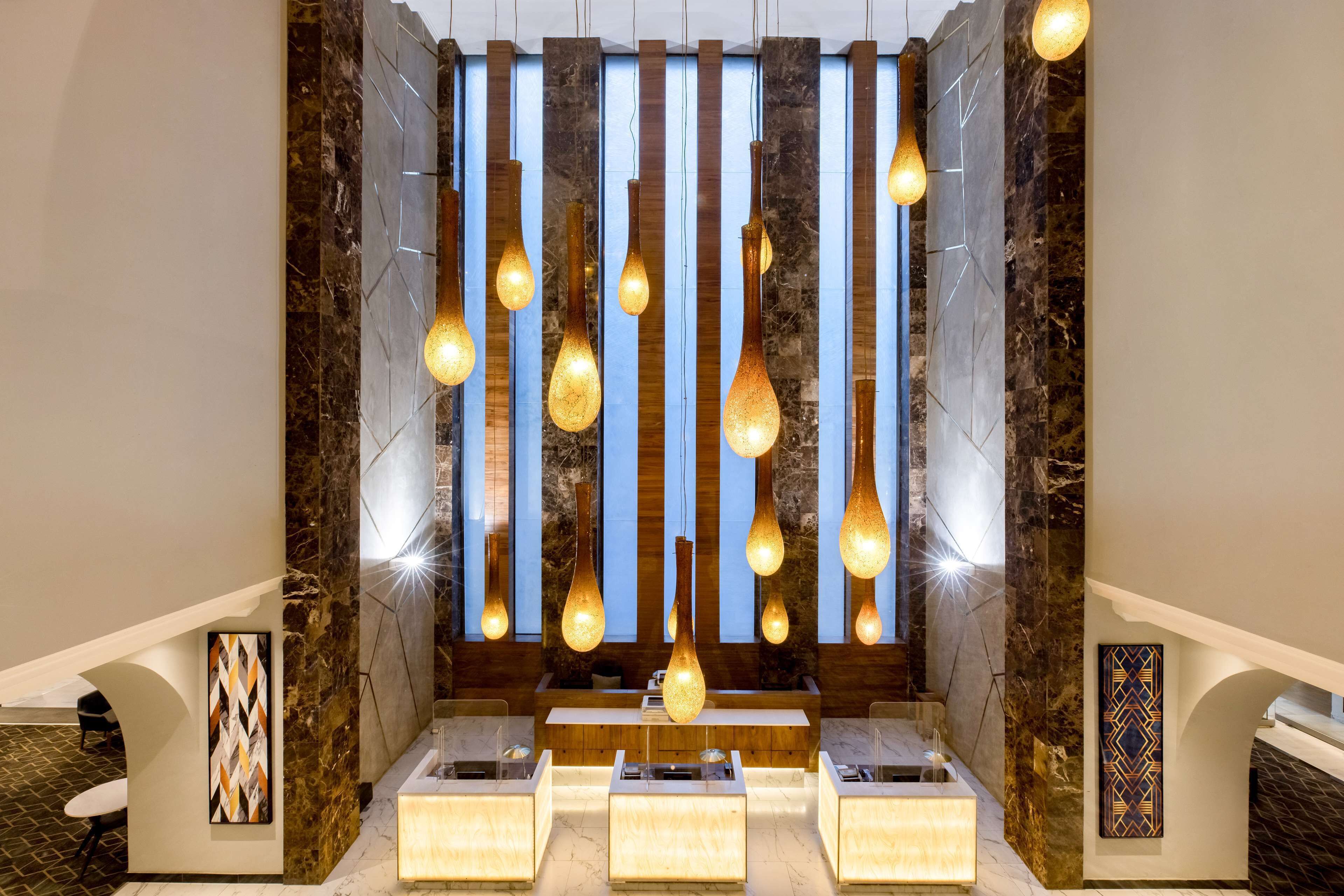 A modern lobby with a reception desk, seating area, and decorative lighting.