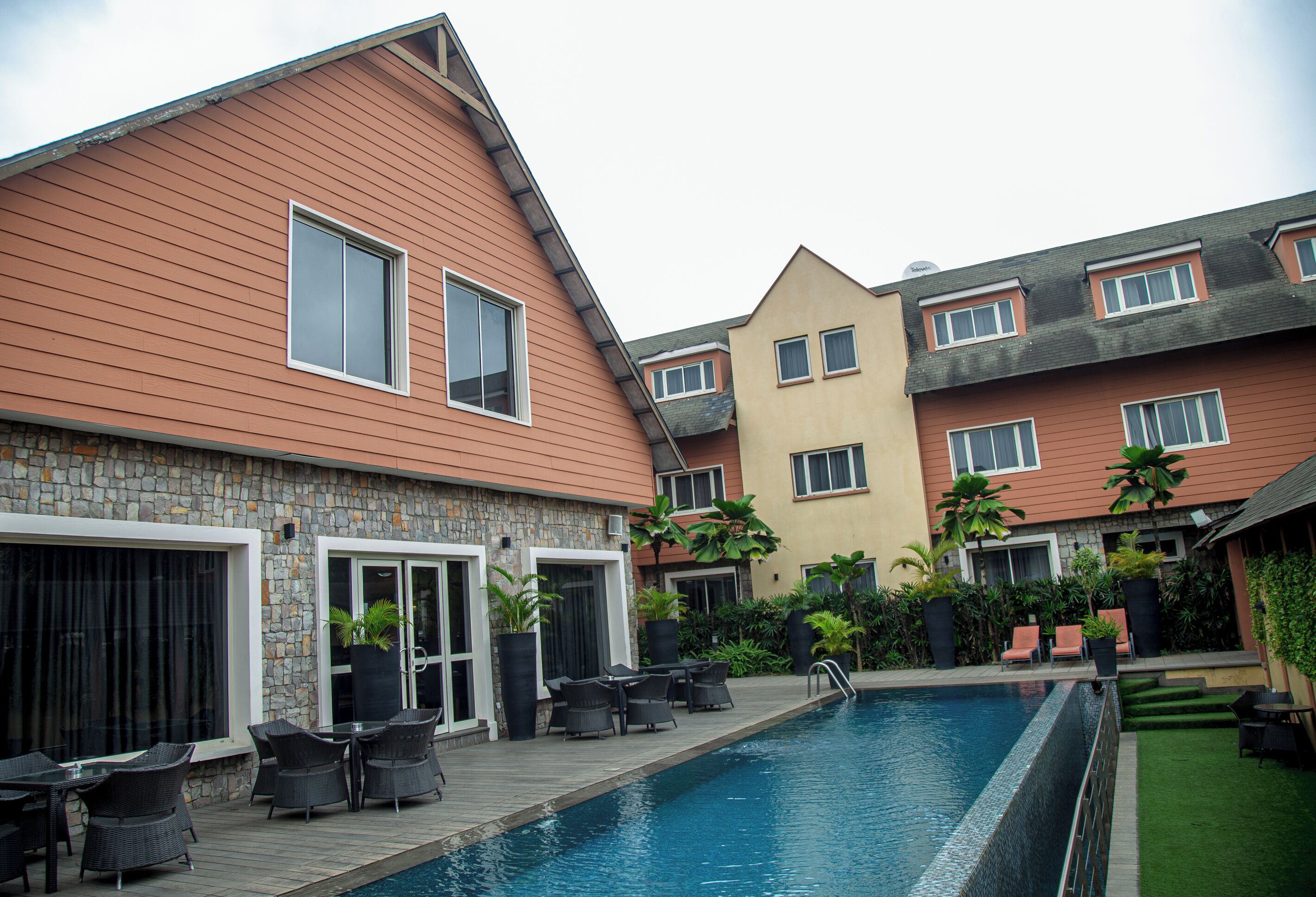 A residential building with a swimming pool, outdoor seating, and a stone facade.