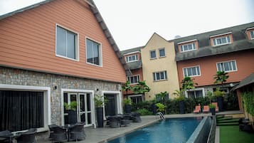 A residential building with a swimming pool, outdoor seating, and a stone facade.