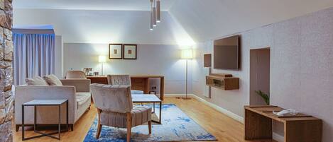 A modern living room with a sofa, chairs, a coffee table, a TV, and a fireplace.