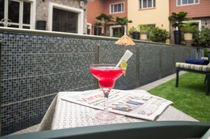 A martini glass with a lime wedge and umbrella on a table with a newspaper.