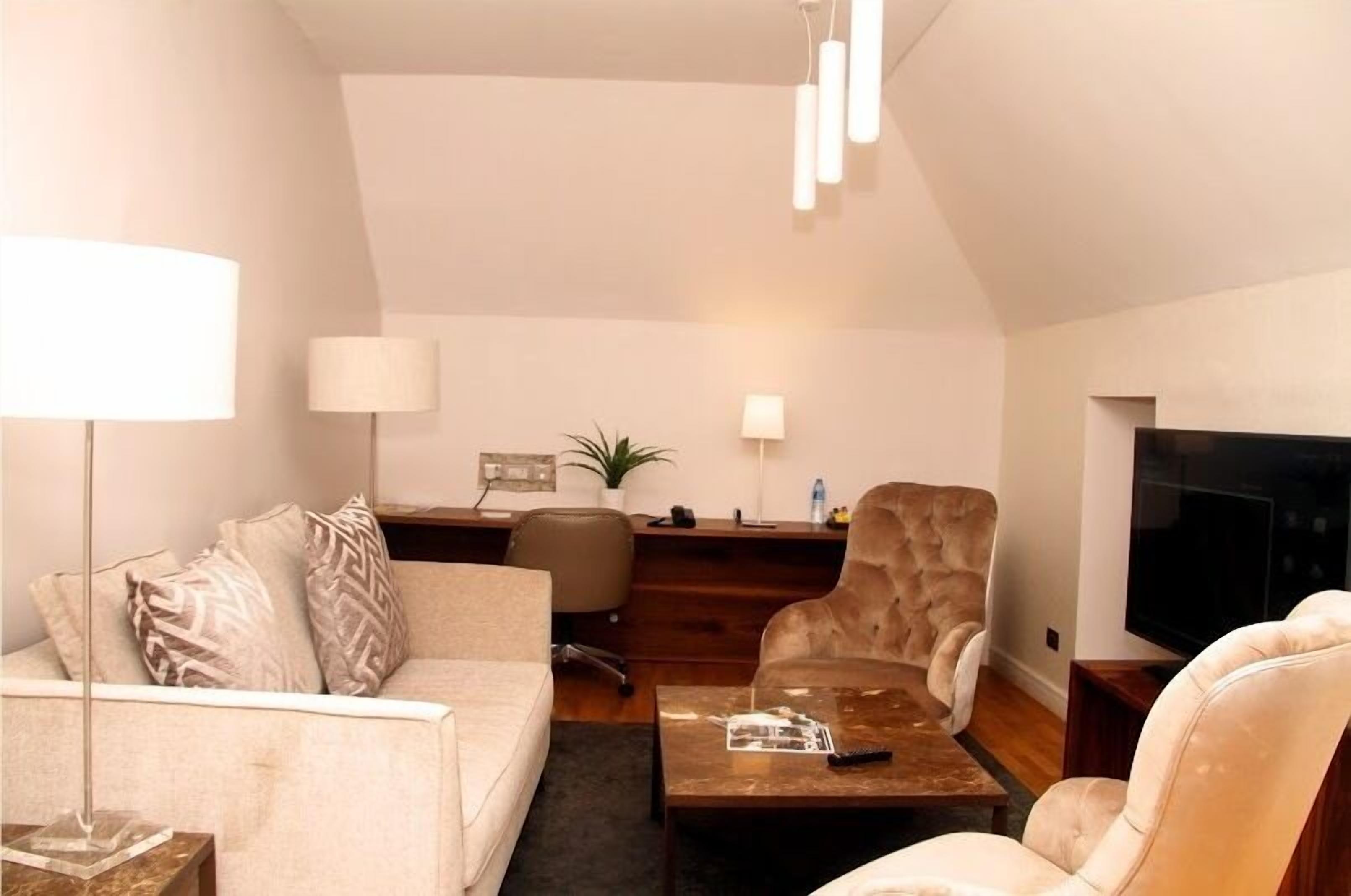A modern living room with a sofa, armchair, coffee table, and TV.