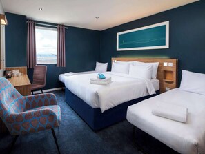 Una habitación de hotel con una cama grande, dos camas más pequeñas, una silla, un escritorio y una ventana con cortinas.