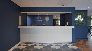 Zona de recepción con pared azul, un reloj y un letrero de neón que dice "85 bar cafe".