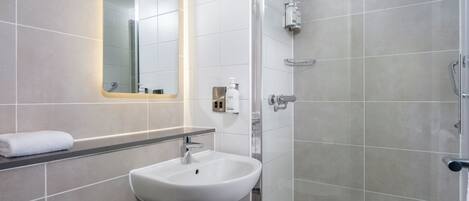A modern bathroom with a sink, mirror, and shower.