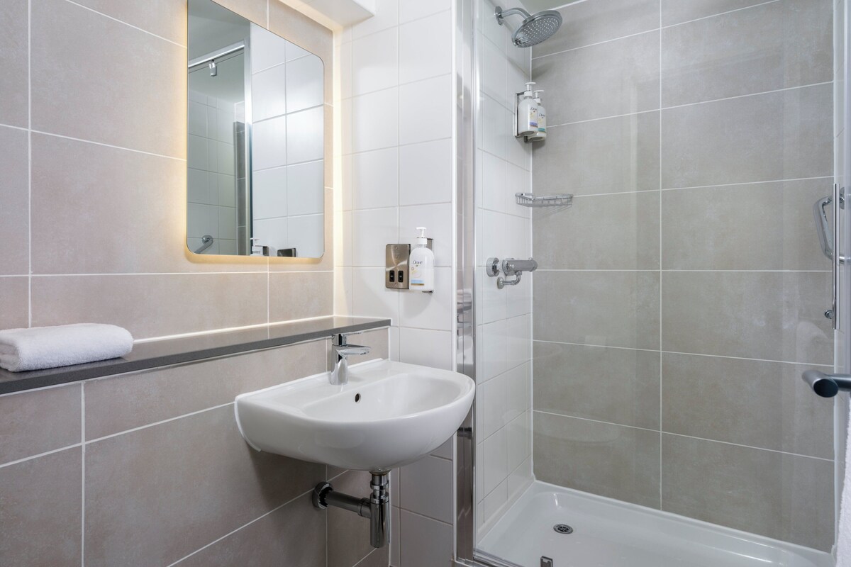 Une salle de bain avec un lavabo blanc, un miroir et une douche.