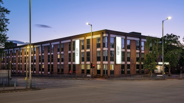 A modern building with a brick facade, large windows, and illuminated signage.